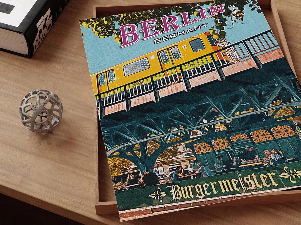 Close-up detail of a Berlin Burgermeister colorful vintage travel poster in a wooden tray on a desk.